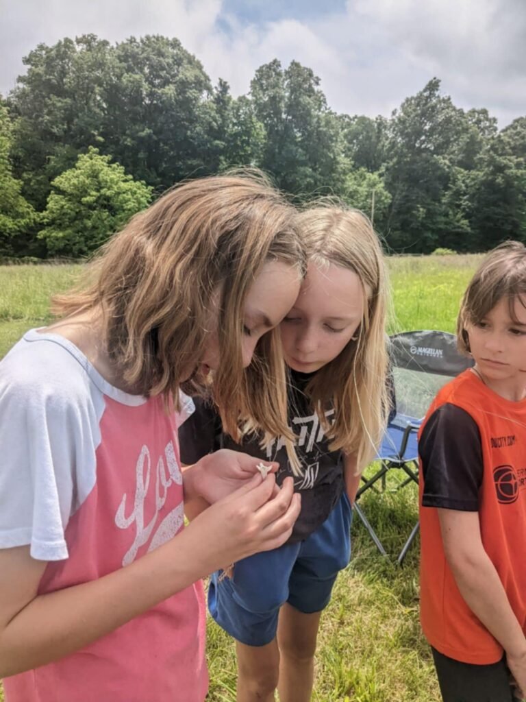 Three girls studying the parts of a flower